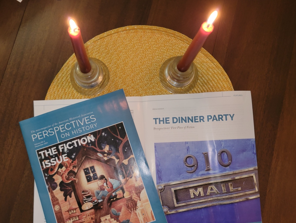 An open magazine on a yellow round placement with two red lit candles.