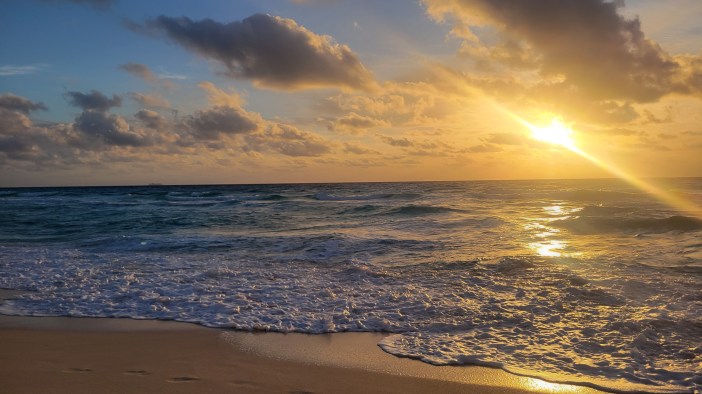 A sunrise over a beach with weaves coming in.