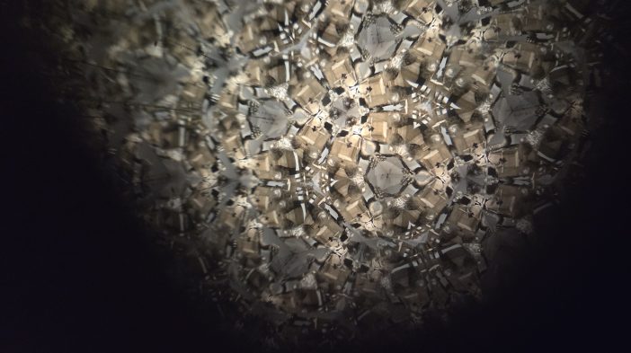 A view of a statue at an exhibition called "The Shape of Power" through a kalidescope lens.