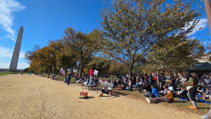 A group of people are gathered with the Washington Monument in the background.